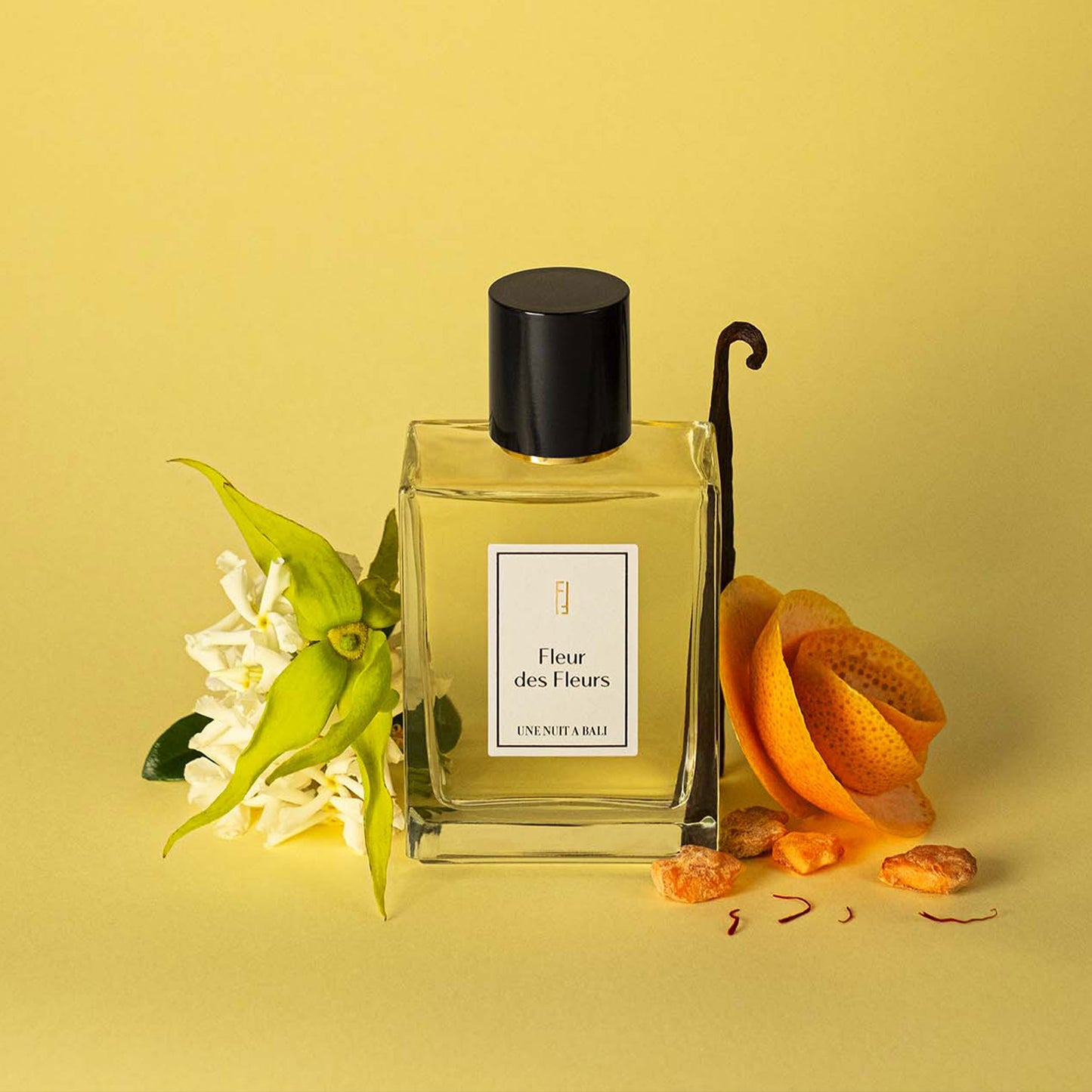 Une Nuit Nomade Fleur des Fleurs niche perfume with vanilla pod, citrus peel, and white floral notes beside the elegant glass fragrance bottle, highlighting a fresh floral-gourmand scent composition