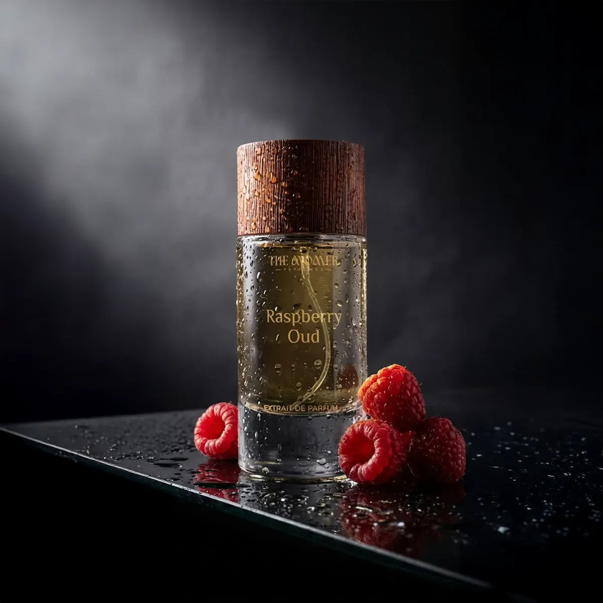 The Momer Raspberry Oud Extrait de Parfum bottle with wooden cap and water droplets, styled with fresh raspberries on dark reflective surface