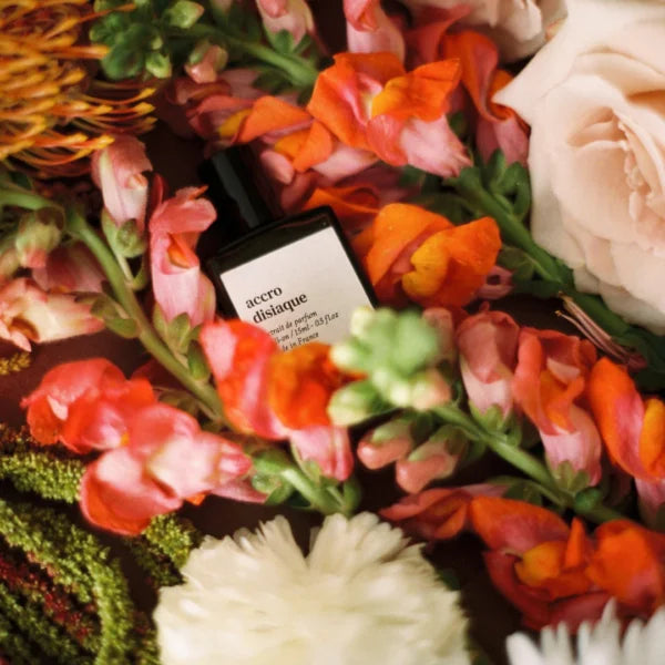 Versatile Paris Accrodisiaque perfume bottle nestled among colorful flowers with soft natural lighting