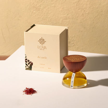 Acuada by LOVA parfum bottle with wooden engraved cap displayed beside branded box in warm natural lighting