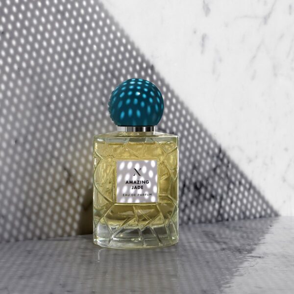 Amazing Jade Eau de Parfum by Les Sœurs de Noé luxury perfume bottle with turquoise cap on marble surface with artistic light shadow background