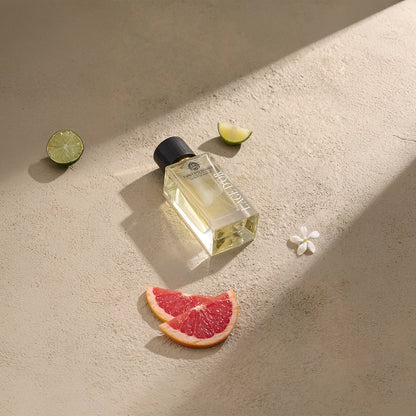 Esprit d’Élégance by L’Âge d’Or luxury perfume bottle styled with grapefruit, lime and white floral accents on beige surface
