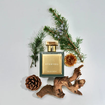 Everveil Eau de Parfum by House of Brandt green and gold perfume bottle styled with pine branches, pinecone and natural wood accents