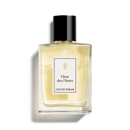 Une Nuit Nomade Fleur des Fleurs Eau de Parfum in clear glass bottle with soft golden fragrance, elegant niche floral perfume with delicate white flower and fresh botanical scent profile
