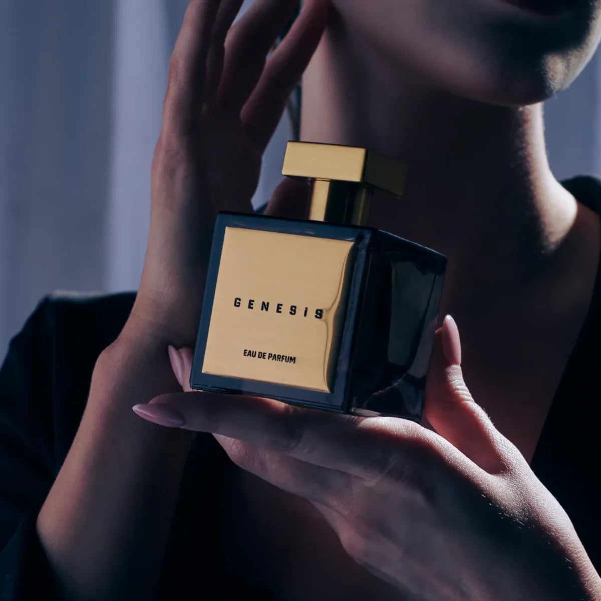 Model holding Genesis Eau de Parfum by House of Brandt, luxury black and gold fragrance bottle, elegant unisex perfume lifestyle image in dramatic lighting