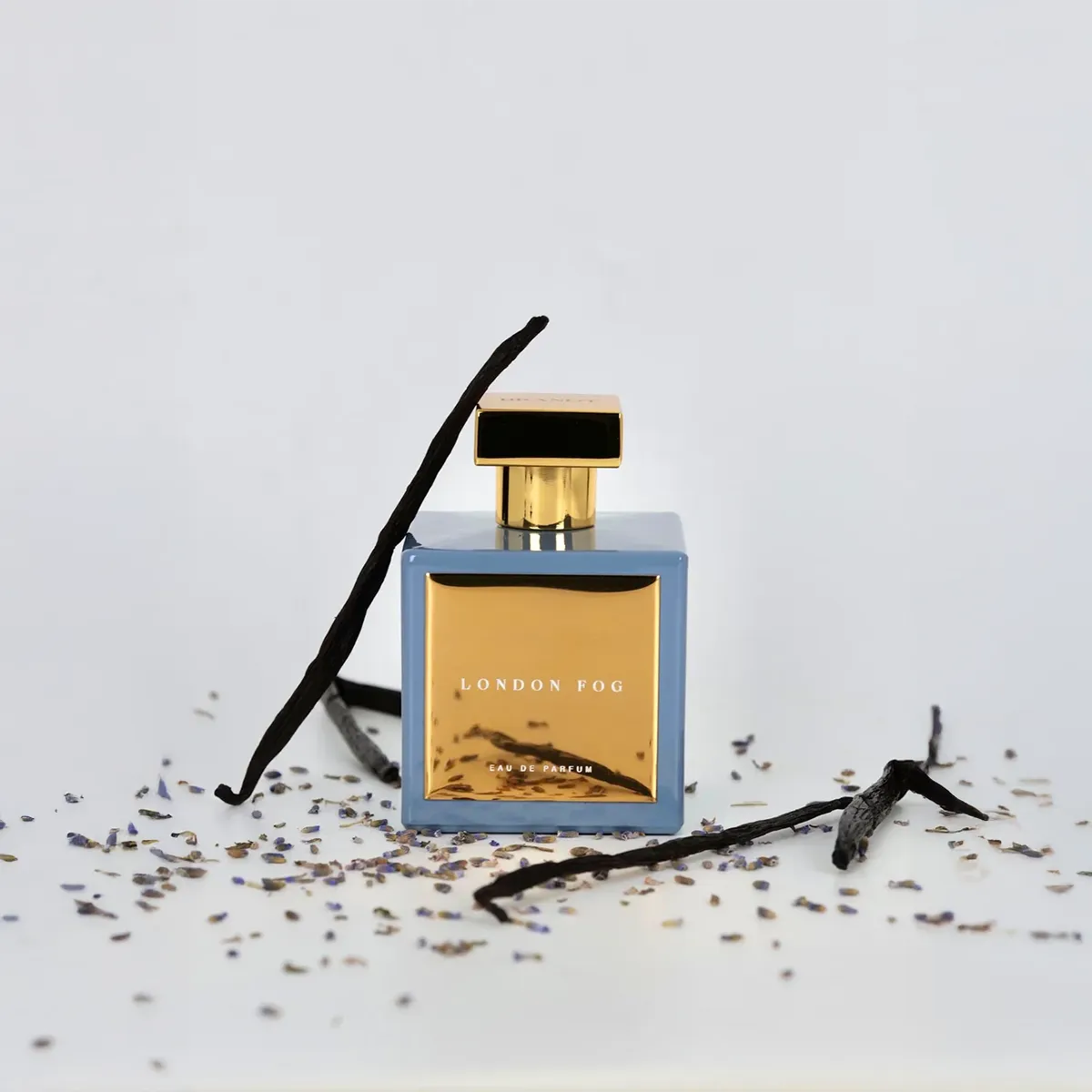London Fog Eau de Parfum by House of Brandt blue and gold perfume bottle with vanilla pods and dried lavender, luxury fragrance product styling image