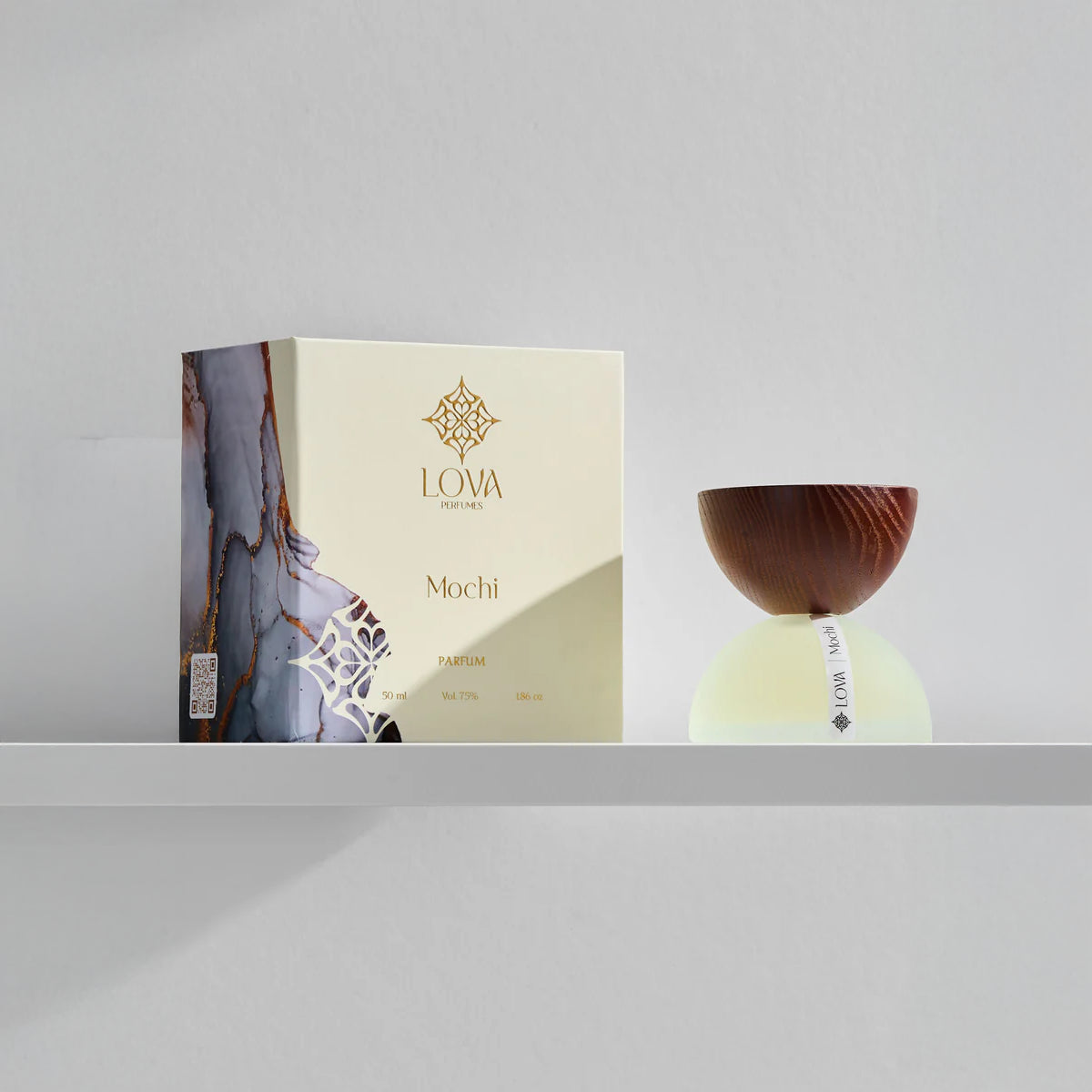 LOVA Mochi Parfum 50ml with frosted glass base and wooden cap displayed beside branded luxury box on minimalist white shelf