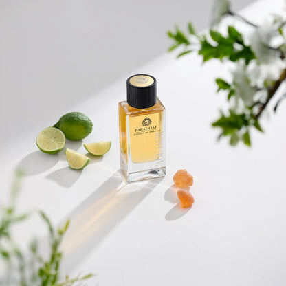 Paradoxe by L’Âge d’Or luxury perfume bottle styled with lime, citrus slices and floral elements on bright background
