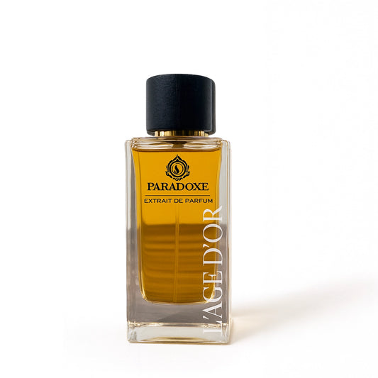 Paradoxe by L’Âge d’Or Extrait de Parfum bottle with golden liquid and black cap on white background
