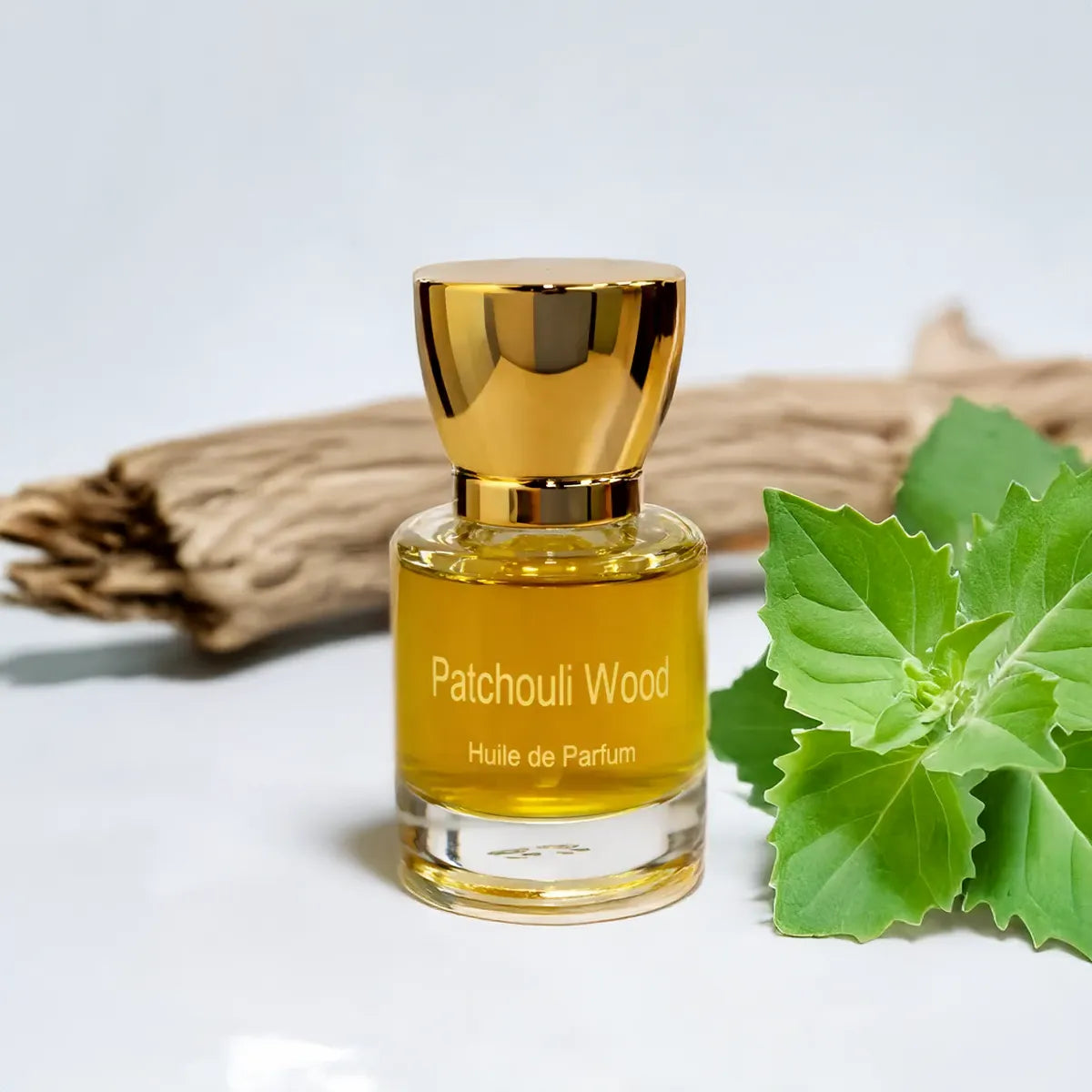 Patchouli Wood huile de parfum surrounded by patchouli leaves and textured wood in a natural setting