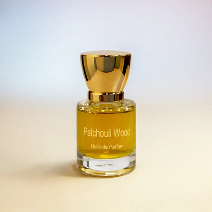 Patchouli Wood huile de parfum bottle with golden liquid and cap on soft gradient background
