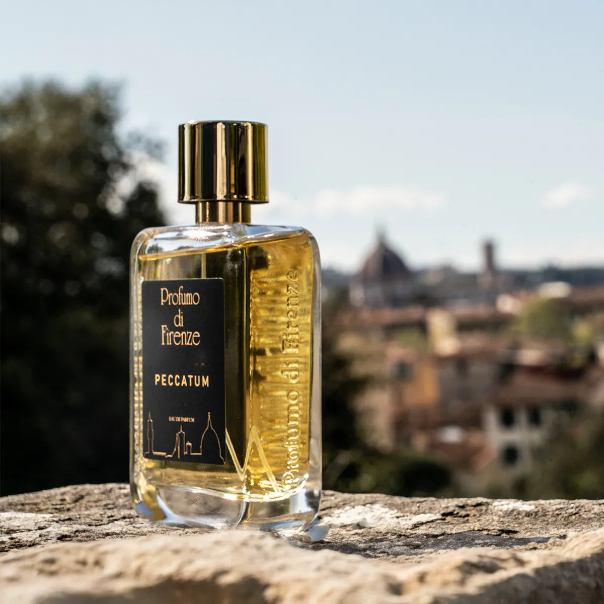Perfume bottle labeled 'Peccatum' by Proflume di Firenze with a scenic background
